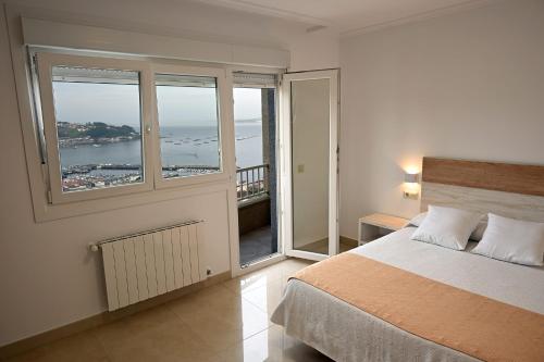 a bedroom with a bed and a view of the ocean at Apartamentos Costas de Bueu in Bueu