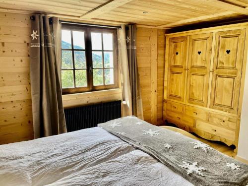 1 dormitorio con cama y ventana en Résidence Chez Simone - Chalets pour 10 Personnes 374, en Flumet