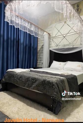 1 dormitorio con 1 cama grande y cortinas azules en Javelin Hotel , Kampala, Uganda en Kampala
