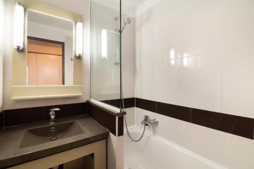 une salle de bain avec un lavabo, une baignoire et un miroir dans l'établissement Résidence le Village de Cap Esterel - maeva Home - Appartement 2 Pièces 4 Personnes - Sélection MAE-3461, à Saint-Raphaël