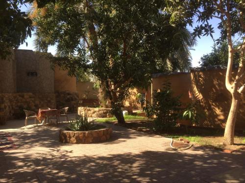 een tuin met een tafel, stoelen en bomen bij New Oasis in Bawati
