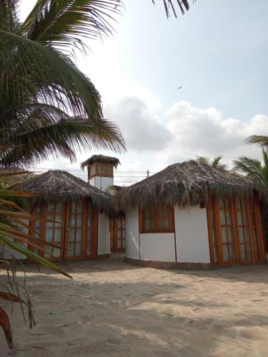 a house with a straw roof and a palm tree at Kalua Plateritos in Plateritos