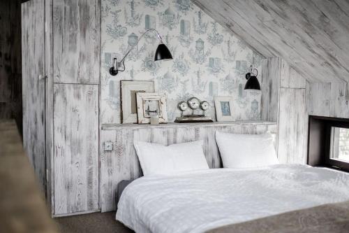 a bedroom with a white bed with a wooden wall at Award-winning cottage on lake Thun- New in Thun