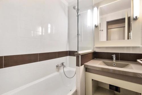 une salle de bain avec un lavabo, une baignoire et un miroir dans l'établissement Résidence le Village de Cap Esterel - maeva Home - Appartement 2 Pièces 5 Personnes - Sélection MAE-3729, à Saint-Raphaël