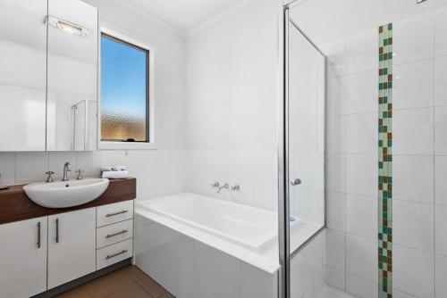 a white bathroom with a sink and a shower at Nice & Quiet 2-Bed by Shops & Airport in Melbourne