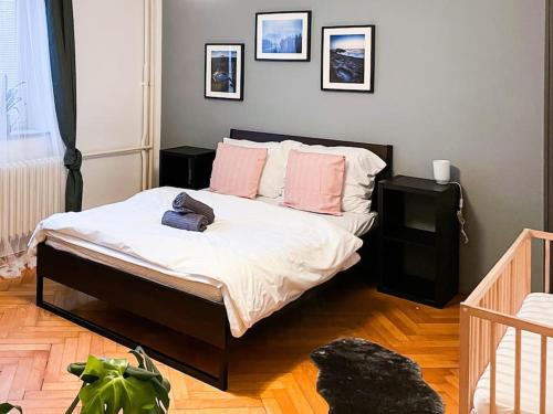 1 dormitorio con 1 cama con sábanas blancas y almohadas rosas en Rodinný byt pro 4 na Brno-střed, en Brno