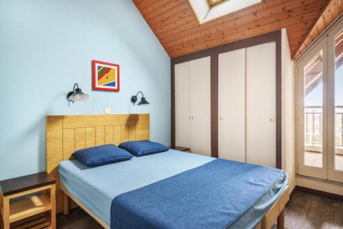 une chambre avec un lit avec des draps bleus et une fenêtre dans l'établissement Résidence Port du Crouesty - maeva Home - 2 Pièces 7 Personnes Confort MAE-5293, à Arzon