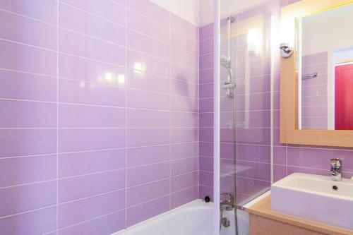 d'une salle de bains pourpre avec baignoire et lavabo. dans l'établissement Village Moliets - maeva Home - 2 pièces 5 personnes Confort MAE-5786, à Moliets-et-Maa