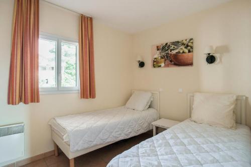une chambre avec deux lits et une fenêtre dans l'établissement Village Pont Royal en Provence - maeva Home - 3 pièces 6 personnes Prestige MAE-6049, à Mallemort