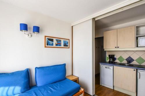 un salon avec un canapé bleu et une cuisine dans l'établissement Résidence Les Océanes - maeva Home - Studio 5 Personnes Confort - vue mer MAE-6032, à Pornichet