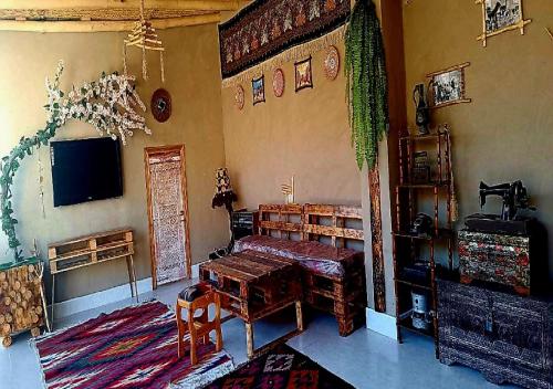 a living room with a table and a tv on the wall at Alifa Lux Guesthouse in Samarkand