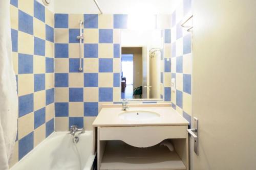 La salle de bains est pourvue d'un lavabo et d'un mur carrelé bleu et blanc. dans l'établissement Hyeres Parc - maeva Home - Appartement 3 pièces 6 personnes Budget MAE-6076, à Hyères