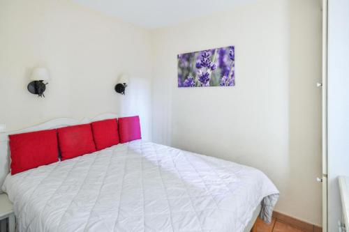 une chambre avec un lit blanc avec des oreillers rouges dans l'établissement Village Pont Royal en Provence - maeva Home - Appartement 2 pièces 6 personnes Sélection MAE-7984, à Mallemort