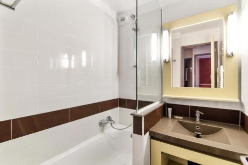 une salle de bain avec un lavabo, une baignoire et un miroir dans l'établissement Résidence le Village de Cap Esterel - maeva Home - Appartement 2 pièces 7 personnes avec coin cabine - Sélection MAE-8077, à Saint-Raphaël