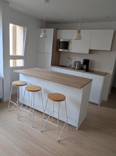 une cuisine avec deux tabourets de bar et un comptoir dans l'établissement Magnifique appartement centre ville, à Hyères