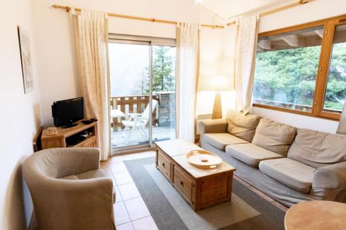sala de estar con sofá y mesa en Les Chalets Petit Bonheur - Chalets pour 6 Personnes 474, en Villarodin-Bourget