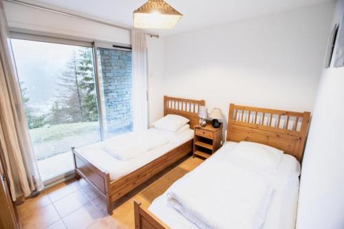 2 camas en una habitación con ventana grande en Les Chalets Petit Bonheur - Chalets pour 6 Personnes 474, en Villarodin-Bourget