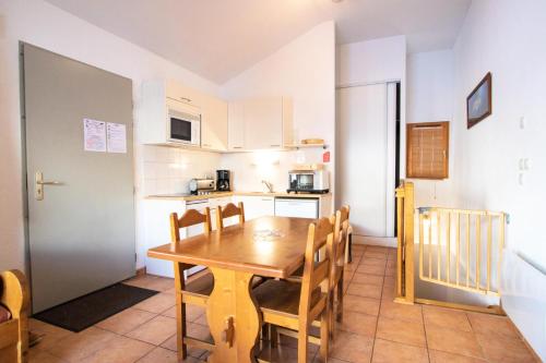 a kitchen and dining room with a wooden table and chairs at Les Chalets Petit Bonheur - Chalets pour 6 Personnes 504 in Villarodin-Bourget