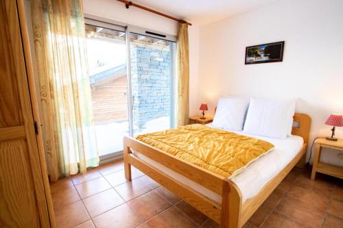 1 dormitorio con cama y ventana grande en Les Chalets Petit Bonheur - Chalets pour 6 Personnes 504, en Villarodin-Bourget
