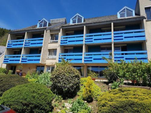 ThiézacにあるLe Castel du Cantal Groupe Village Faniの青いバルコニー付きの大きなアパートメントビル