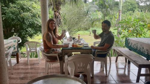 a man and woman sitting at a table with drinks at Rancho Esperança, pouso e comida a lenha in Paraty