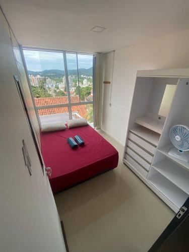 una camera con letto rosso e frigorifero aperto di Hospedaria Trindade a Florianópolis