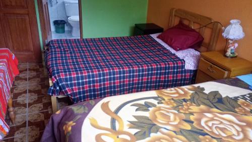 a bedroom with two beds and a plaid bedspread at Teach Huaraz Peru in Huaraz