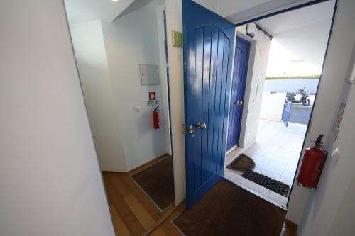 a blue door leading into a hallway with aoyer with a dog at Cosy Studio Azores Beach in Ponta Delgada