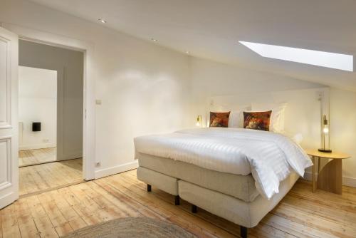 biała sypialnia z dużym łóżkiem i świetlikiem w obiekcie Our Bird's Nest in the Heart of Antwerp w Antwerpii