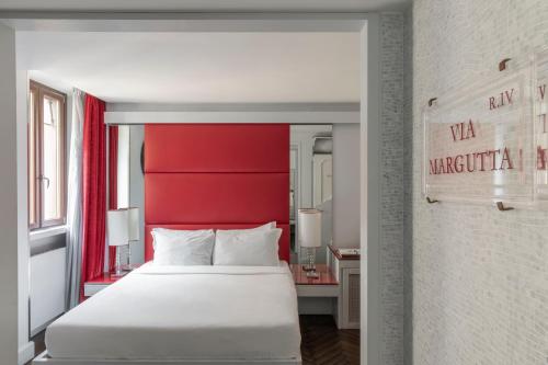 Schlafzimmer mit einem weißen Bett und einem roten Kopfteil in der Unterkunft BDB Rooms Margutta in Rom
