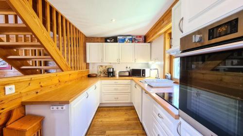 une cuisine avec des armoires blanches et un plancher en bois dans l'établissement Résidence Hameau - Chalet spacieux · Sauna · Cheminée MAE-7349, à Flaine