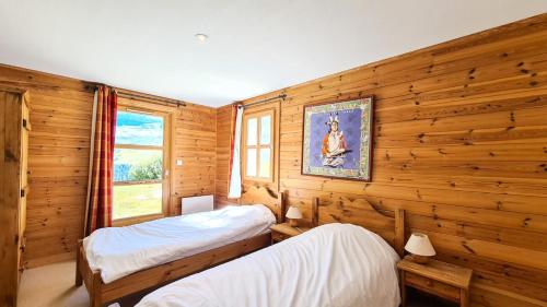 deux lits dans une chambre aux murs en bois dans l'établissement Résidence Hameau - Chalet spacieux · Sauna · Cheminée MAE-7349, à Flaine