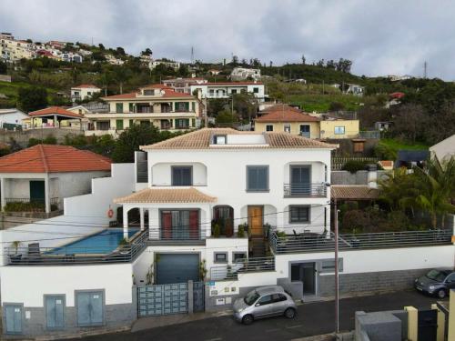 a white house with a car parked in front of it at 3 bedrooms house with private pool terrace and wifi at Funchal 3 km away from the beach in Funchal