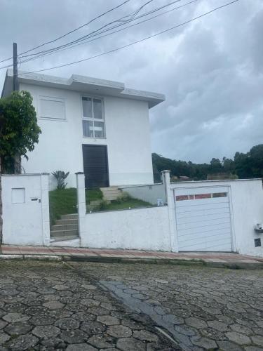 a white house with a gate and a garage at Hospedaria Trindade in Florianópolis