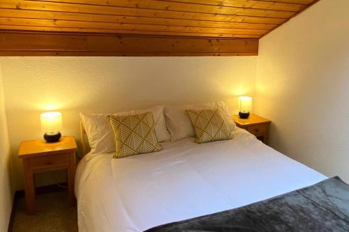 a bedroom with a white bed with two lamps at Résidence Le Vieux Moulin - 4 Pièces pour 6 Personnes 144 in Morzine