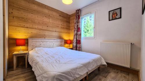 une chambre avec un grand lit et une fenêtre dans l'établissement Résidence Les Pleiades - Appartement spacieux et lumineux · Centre station · Balcon · Parking couvert MAE-7355, à Flaine