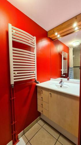 La salle de bains rouge est pourvue d'un lavabo et d'un miroir. dans l'établissement Résidence Les Pleiades - Appartement spacieux et lumineux · Centre station · Balcon · Parking couvert MAE-7355, à Flaine