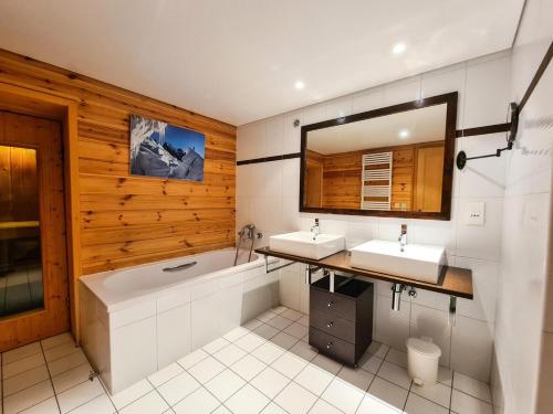 a bathroom with two sinks and a tub and a mirror at Résidence Hameau - Chalets pour 8 Personnes 57 in Flaine