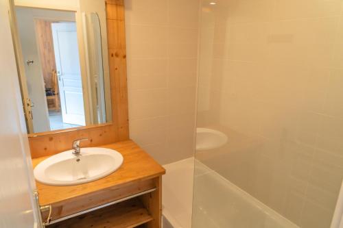 uma casa de banho com um lavatório, um espelho e uma banheira em Résidence Le Balcon Des Airelles - 2 Pièces pour 4 Personnes 094 em Les Orres