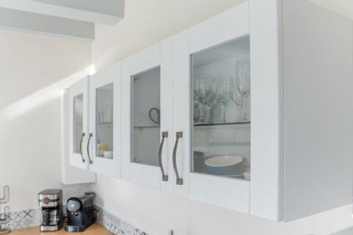 a kitchen with white cabinets with glassware at KER HIR - Charmante maison bretonne tout confort in Landunvez