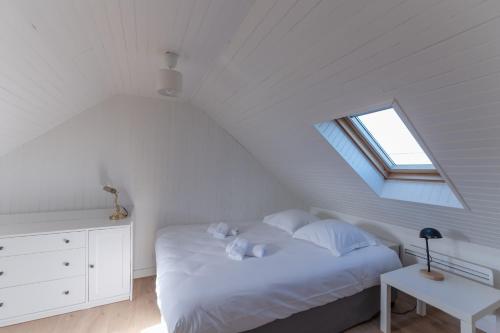ein weißes Schlafzimmer mit einem Bett und einem Fenster in der Unterkunft KER HIR - Charmante maison bretonne tout confort in Landunvez