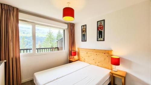 ein Schlafzimmer mit einem weißen Bett und einem Fenster in der Unterkunft Résidence Les Pleiades - 3 Pièces pour 6 Personnes 81 in Flaine