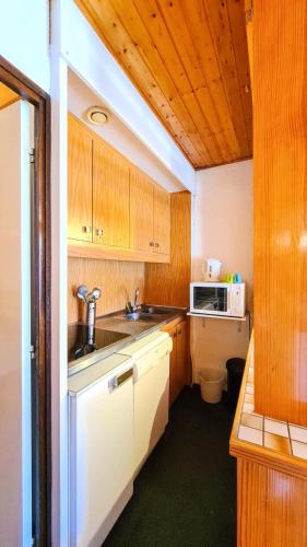 une petite cuisine avec un évier et un micro-ondes dans l'établissement Résidence Andromede - Studio confortable · Entre pistes et commerces · Balcon MAE-7395, à Flaine