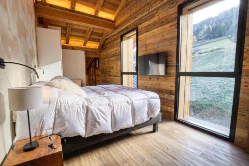 a bedroom with a bed and a large window at Chalet - Chalets 101 in Notre-Dame-de-Bellecombe