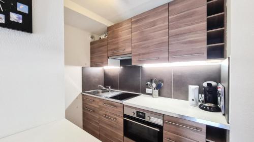 une cuisine avec des armoires en bois et un évier dans l'établissement Résidence La Petite Ourse - Studio neuf · Centre station · Balcon MAE-7402, à Flaine