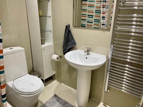 uma casa de banho com um WC branco e um lavatório. em Sudbury Hill Bedroom with Private Bathroom em Harrow