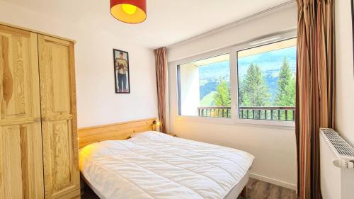 une chambre avec un lit et une grande fenêtre dans l'établissement Résidence Les Pleiades - Appartement lumineux · Centre station · Parking couvert · Balcon MAE-7409, à Flaine