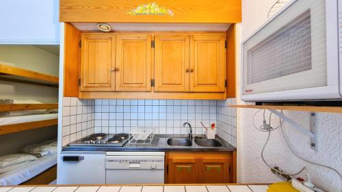 een kleine keuken met houten kasten en een wastafel bij Résidence Andromede - Studio pour 4 Personnes 11 in Flaine