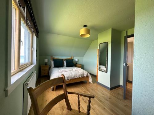una camera da letto con un letto e una sedia di Braighe Cottage a Stornoway