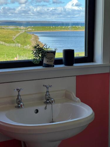 a sink in front of a window with a view of the ocean at Braighe Cottage in Stornoway
